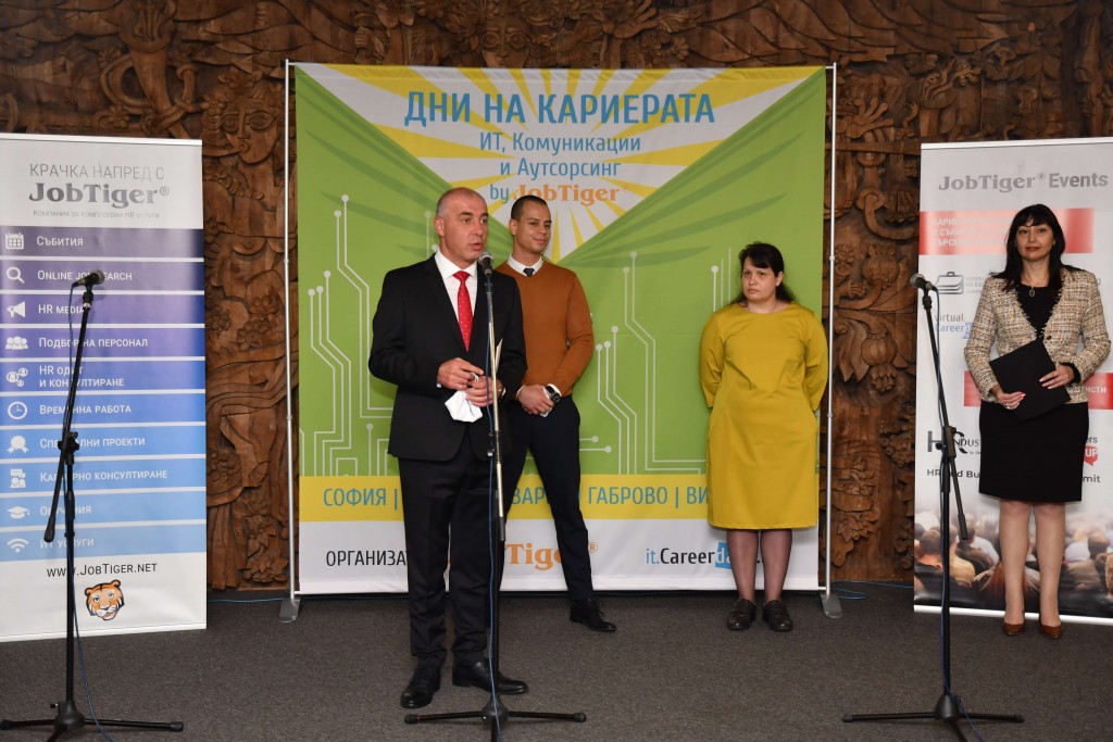 A group of people standing in front of a sign posing for the cameraDescription automatically generated